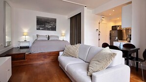 Ein modernes Hotelzimmer mit Bett, einer Sitzecke, einem Schreibtisch und einer Küchenzeile.