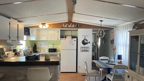 Una cucina con isola centrale, mobili bianchi, un frigorifero e un'area pranzo con tavolo e sedie.