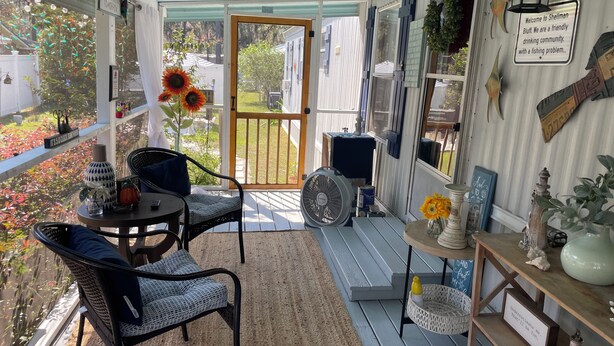 Un portico accogliente con tavolo e sedie, un ventilatore e diversi oggetti decorativi.