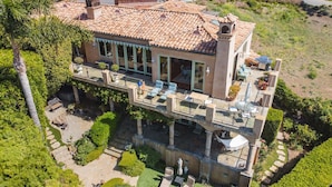 A large, two-story house with a tiled roof, multiple balconies, and a well-maintained garden. - MALIBU LUXURY BEACH VILLA - 5-STAR REVIEWS! (Malibu)