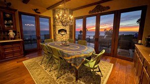 A dining area with a round table, chairs, a chandelier, and a stone fireplace. - MALIBU LUXURY BEACH VILLA - 5-STAR REVIEWS! (Malibu)