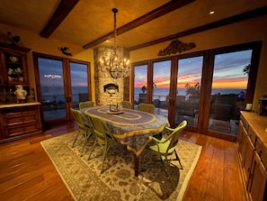 A dining area with a round table, chairs, a chandelier, and a stone fireplace. - MALIBU LUXURY BEACH VILLA - 5-STAR REVIEWS! (Malibu)
