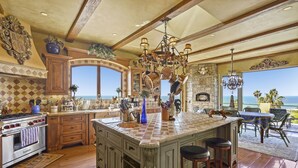 A spacious kitchen with a large island, wooden cabinets, and a view of the ocean. - MALIBU LUXURY BEACH VILLA - 5-STAR REVIEWS! (Malibu)