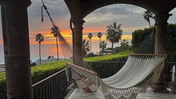 A hammock on a balcony with stone columns, overlooking a sunset with palm trees and a view of the ocean. - MALIBU LUXURY BEACH VILLA - 5-STAR REVIEWS! (Malibu)