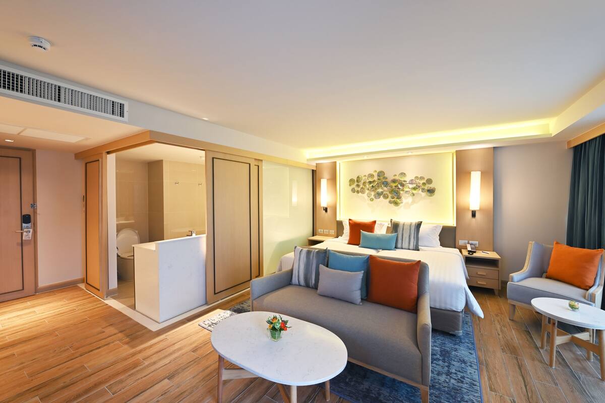A hotel room with a bed, a sofa, a desk, and a small table.