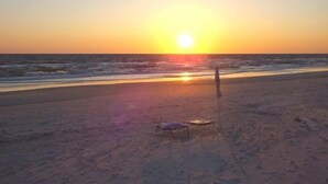 A beach with a sunset, two empty beach chairs, and a volleyball net. - Lots of Space, Beachview, Easy ~ Coastal Sunshine (Cape San Blas)