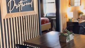 Un comedor con una mesa de madera y sillas negras, un letrero que dice "The Driftwood" y una pared de listones de madera.