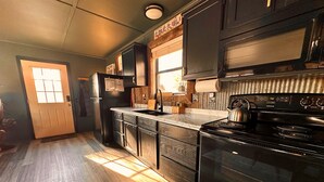 Una cocina con refrigerador negro, estufa y armarios.