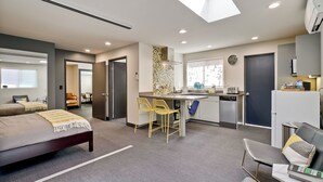 Una habitación de hotel moderna con una cama, un escritorio y una kitchenette.