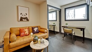 Una sala de estar moderna con un sofá de cuero, una mesa redonda de centro y una obra de arte de un panda en la pared.