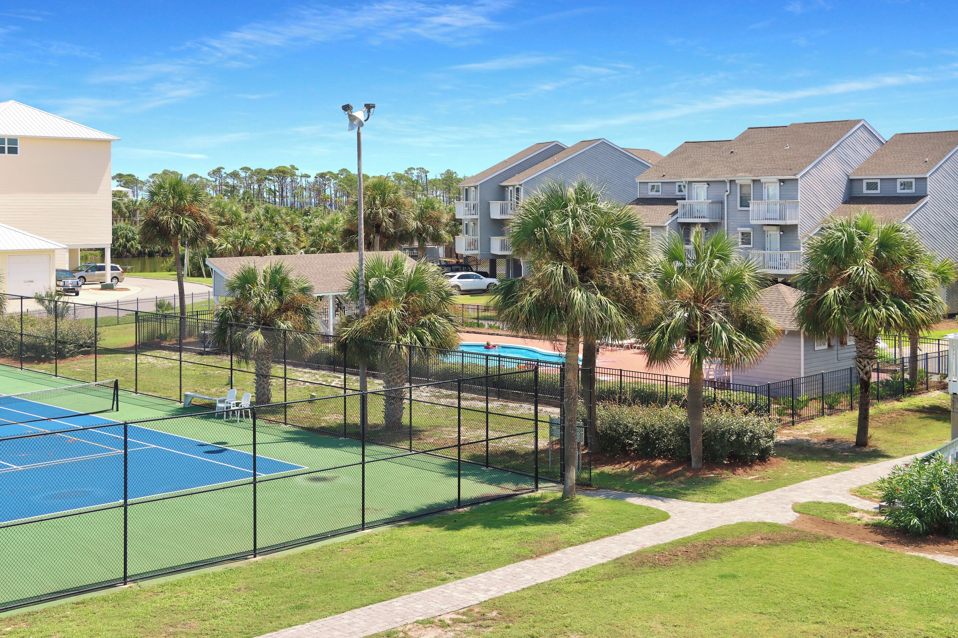 A residential area with a tennis court, a pool, and apartment buildings.