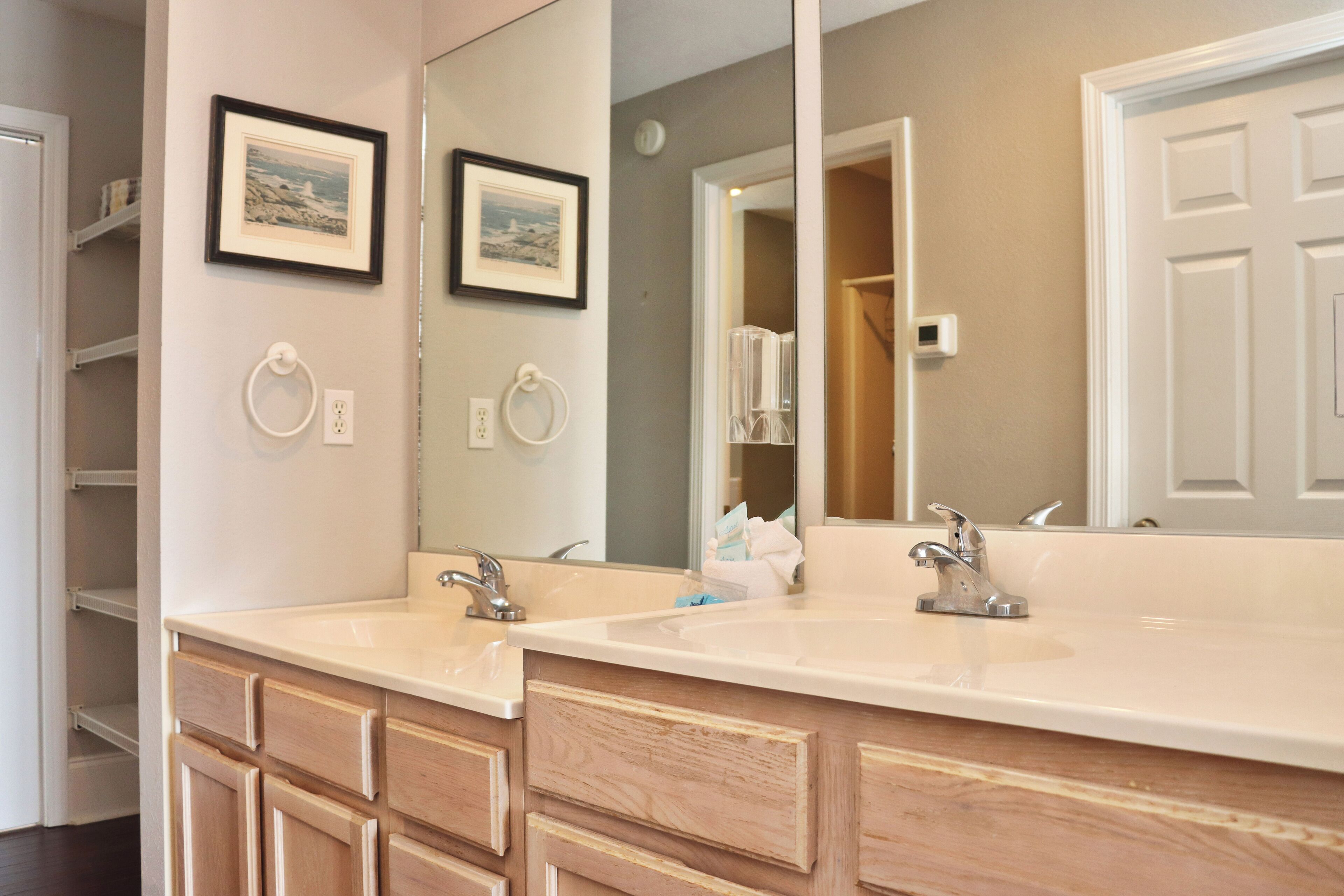 A bathroom with a double sink vanity, wooden cabinets, and a large mirror.