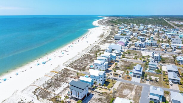 An aerial view of a coastal area with a beach, residential buildings, and a clear sky. - Gulf View, Gated Community with Pool, WiFi ~ Waterside Village Condo 302 (Mexico Beach)