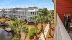 A row of townhouses with a wooden deck and palm trees. - Gulf View, Gated Community with Pool, WiFi ~ Waterside Village Condo 302 (Mexico Beach)