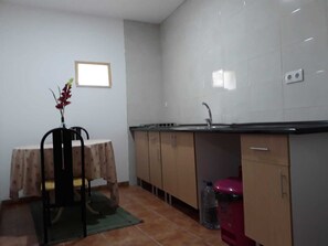 A small kitchen with a tiled backsplash, a sink, and a table with a chair. - Beautiful family house with pool in the center of a typical village of Portugal (Vila Nova de Poiares)
