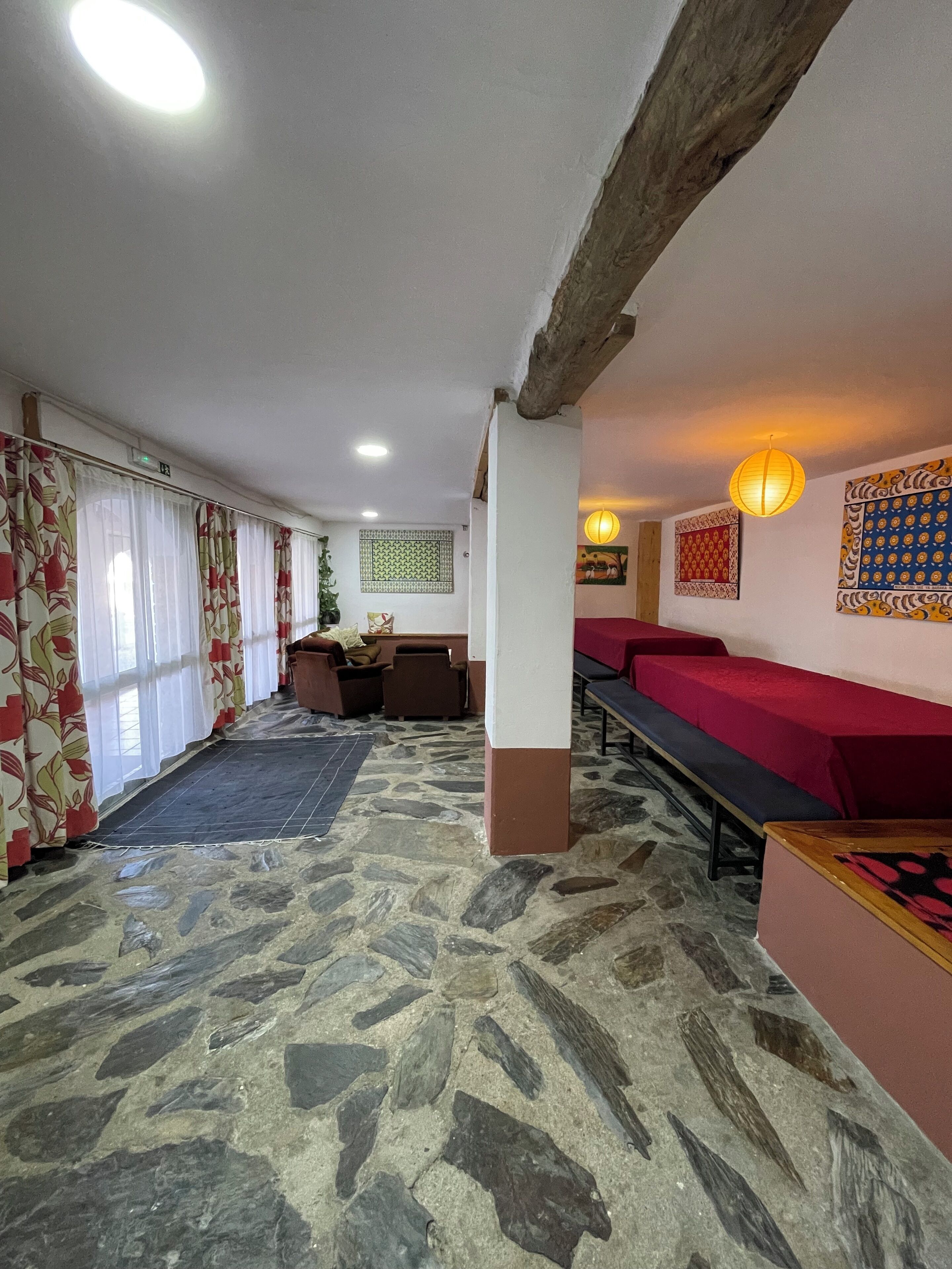 A stone-floored lobby with a seating area, a wooden ceiling beam, and patterned wall decorations.
