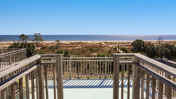 Une terrasse en bois offrant une vue sur la plage et l’océan.