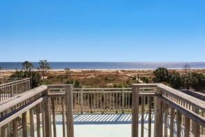 Une terrasse en bois offrant une vue sur la plage et l’océan.