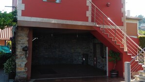 A two-story building with a red exterior, a stone foundation, and a red staircase leading to the upper floor. - "EIRA VELLA" Holiday house, (from € 30 day / month). (Pontevedra)