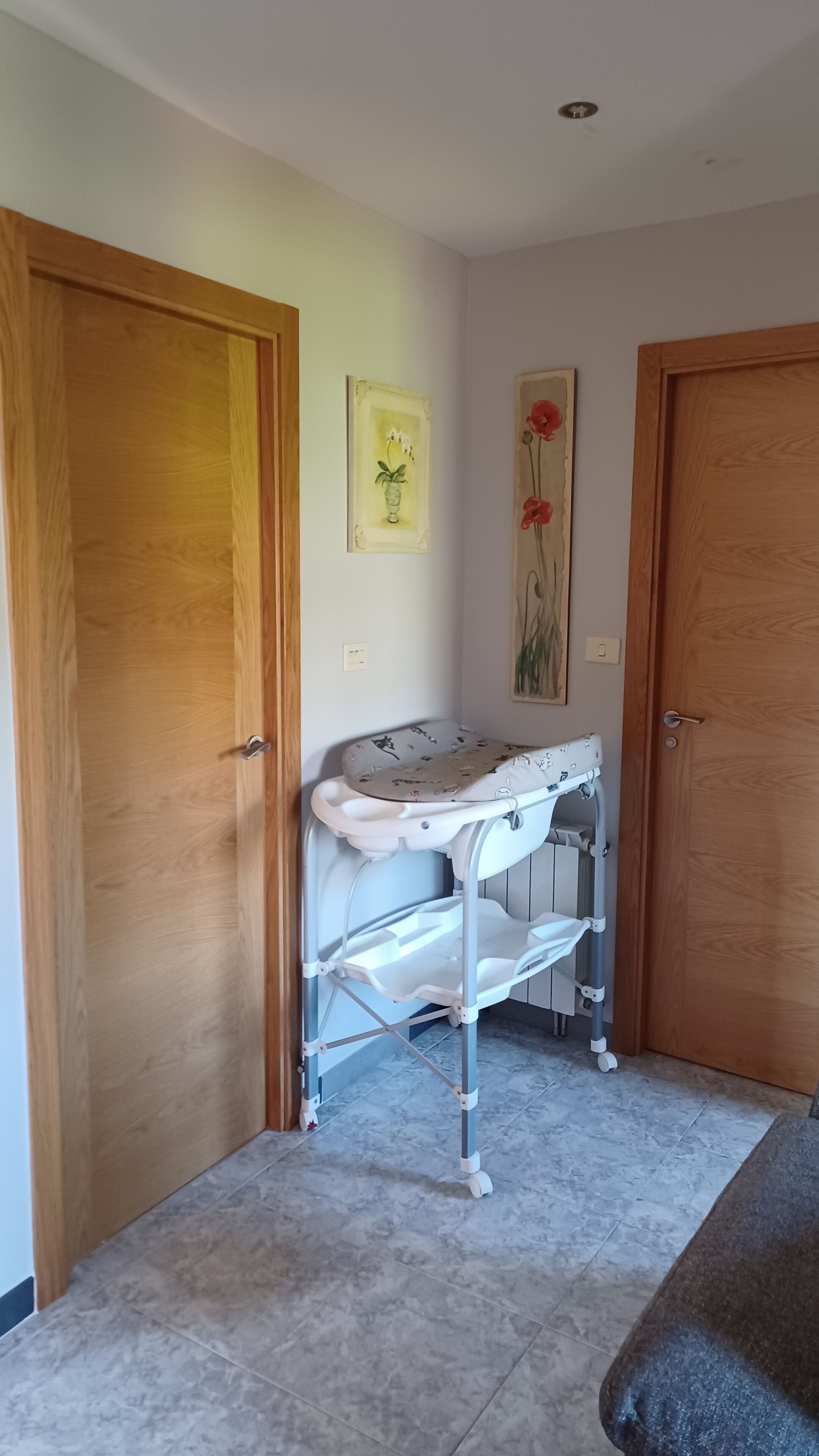 Una habitación con cambiador para bebés, puertas de madera y dos obras de arte colgadas en la pared.
