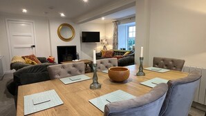 Een moderne woonkamer met een open haard, een televisie en een eethoek met een houten tafel en stoelen.