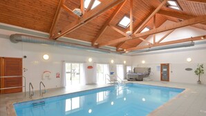 Una piscina con techo de madera, un jacuzzi y una puerta con la inscripción 'Ladies'.