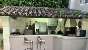A kitchen with a tiled roof, a refrigerator, a coffee machine, and two bar stools. - PRETTY PROVENCAL VILLA WITH POOL (Le Tignet)