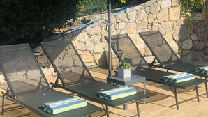 Outdoor lounge chairs with cushions, a stone wall, and a potted plant. - PRETTY PROVENCAL VILLA WITH POOL (Le Tignet)