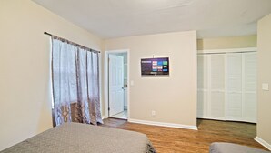 Ein Schlafzimmer mit einem Bett, einem an der Wand montierten Fernseher und einem Schrank mit Schiebetüren.
