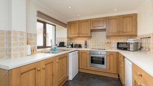 Une cuisine moderne avec des meubles en bois, un lave-vaisselle, une cuisinière et un four à micro-ondes.