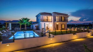 A modern two-story house with a swimming pool, outdoor seating, and a well-lit patio area. - Villa Orchard (Zakynthos)