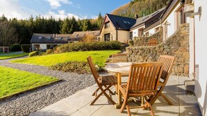 A stone house with a patio, outdoor seating, and a well-maintained lawn.