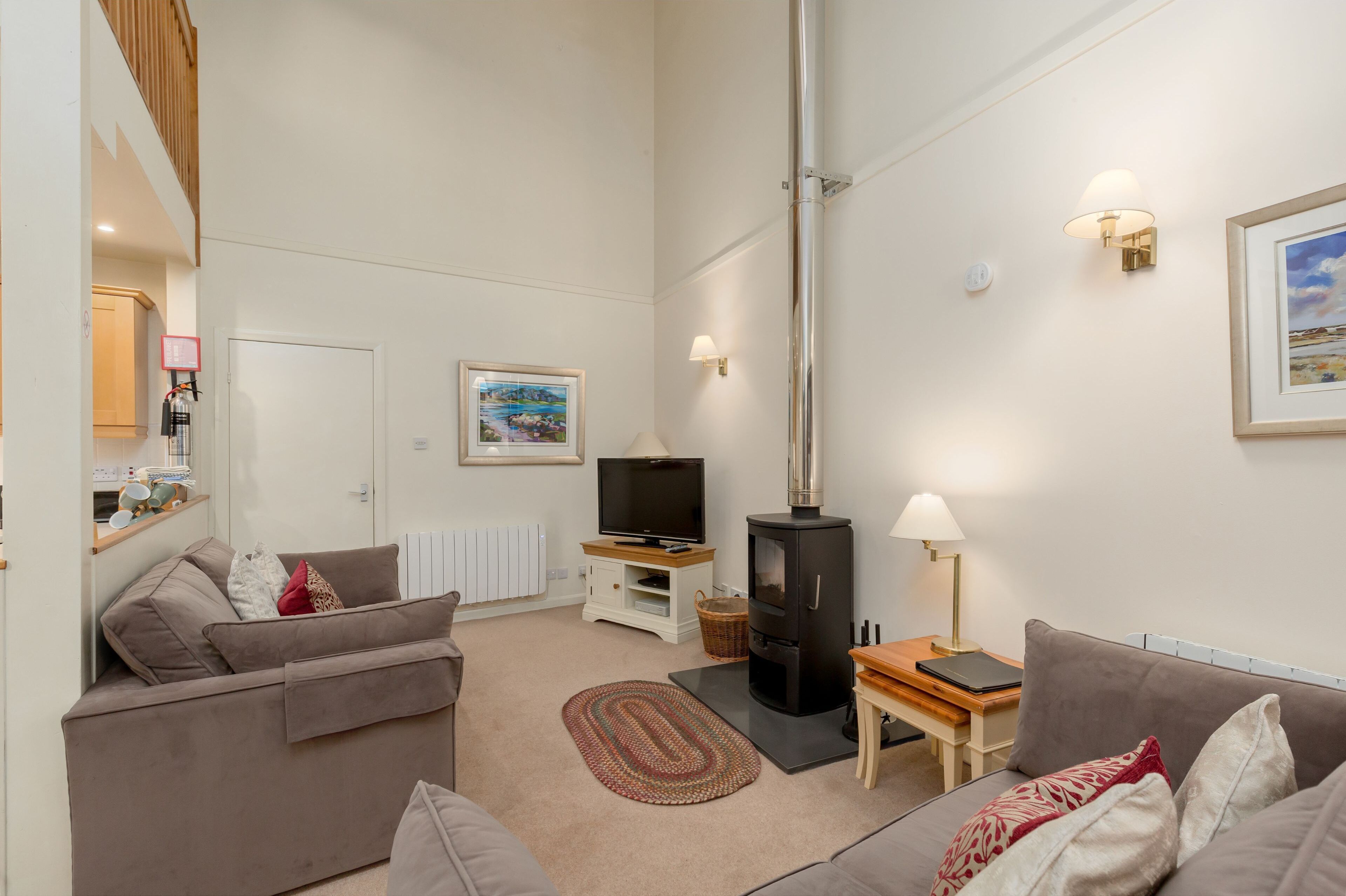 Een woonkamer met een bank, een televisie, een open haard en een lamp.