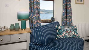 A room with a sofa, a table with a lamp, and a window with curtains. - Pier House Two -  Loch-side semi-detached house sleeping up to 10 (Oban)