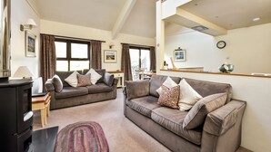 A spacious living room with two sofas, a fireplace, and a dining area.