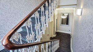Eine Treppe mit aufwendigen, weißen Geländern und einem dunkel teppichbesetzten Boden.