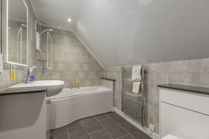 A modern bathroom with a bathtub, a sink, and a mirror. - Walled Garden Mews 11 -  an apartment that sleeps up to 6 guests (Oban)