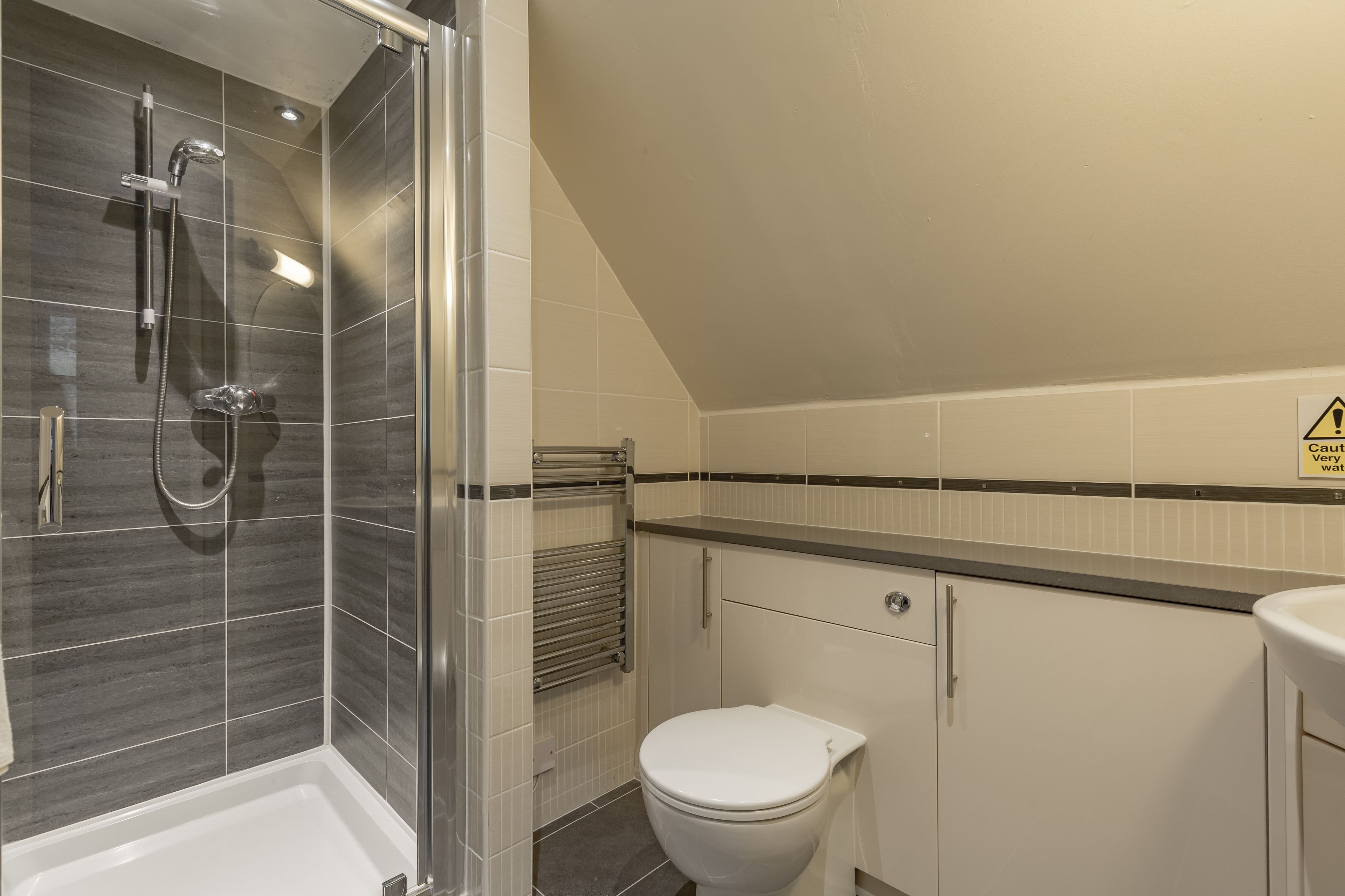Un bagno moderno con doccia, servizi igienici e portasciugamani.