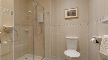 A bathroom with a glass-enclosed shower, a toilet, and a framed picture on the wall.