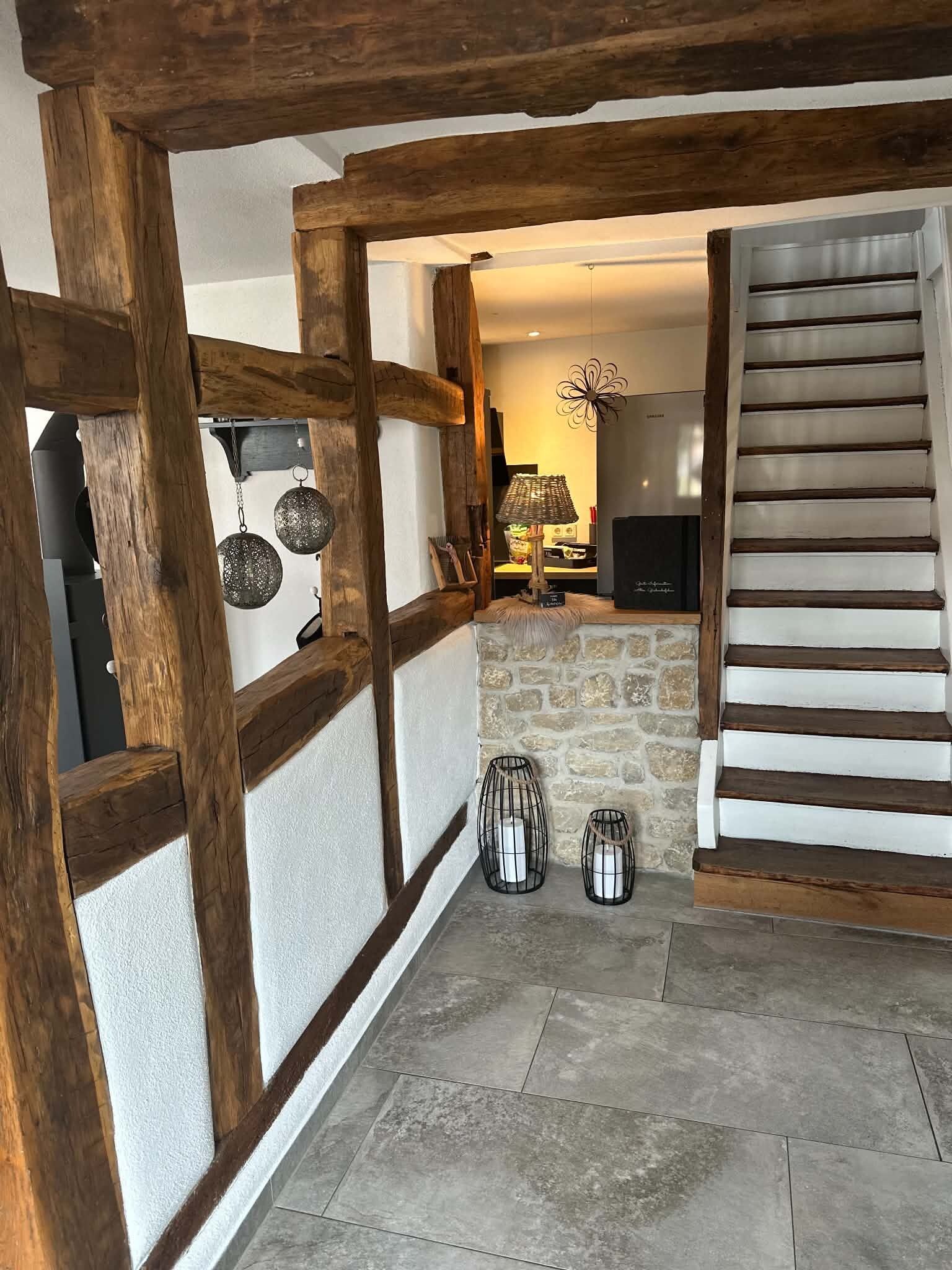 Un intérieur rustique avec des poutres apparentes, un mur en pierre et un escalier.