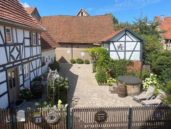 A traditional half-timbered building with a tiled roof, a garden with potted plants and a wooden barrel, and a sign indicating a restaurant. - 5 * Romantic, historic half-timbered house from 1623 - stove & infrared sauna (Stetten)