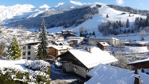 A snow-covered mountain town with buildings and a ski slope. - RESIDENCE 2-235 - Village-center studio, close to the slopes - Wi-Fi - Garage (La Clusaz)