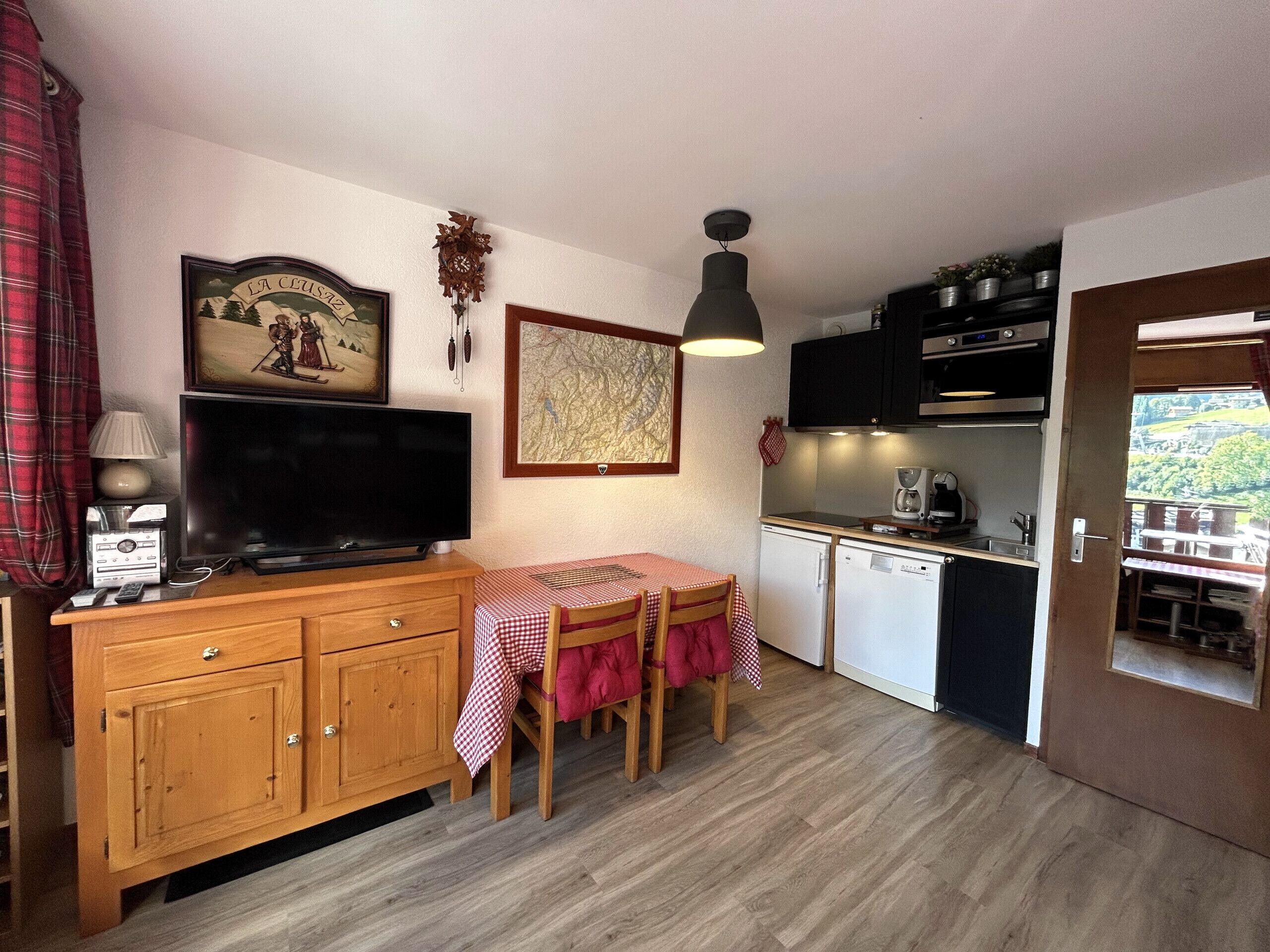 Una cocina compacta con comedor, televisor y un refrigerador pequeño.