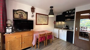 A compact kitchen with a dining area, a television, and a small refrigerator. - RESIDENCE 2-235 - Village-center studio, close to the slopes - Wi-Fi - Garage (La Clusaz)