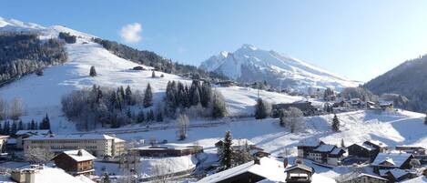 A snow-covered mountain village with traditional wooden houses and a ski slope.