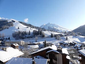 Ein verschneites Bergdorf mit traditionellen Holzhäusern und einer Skipiste.