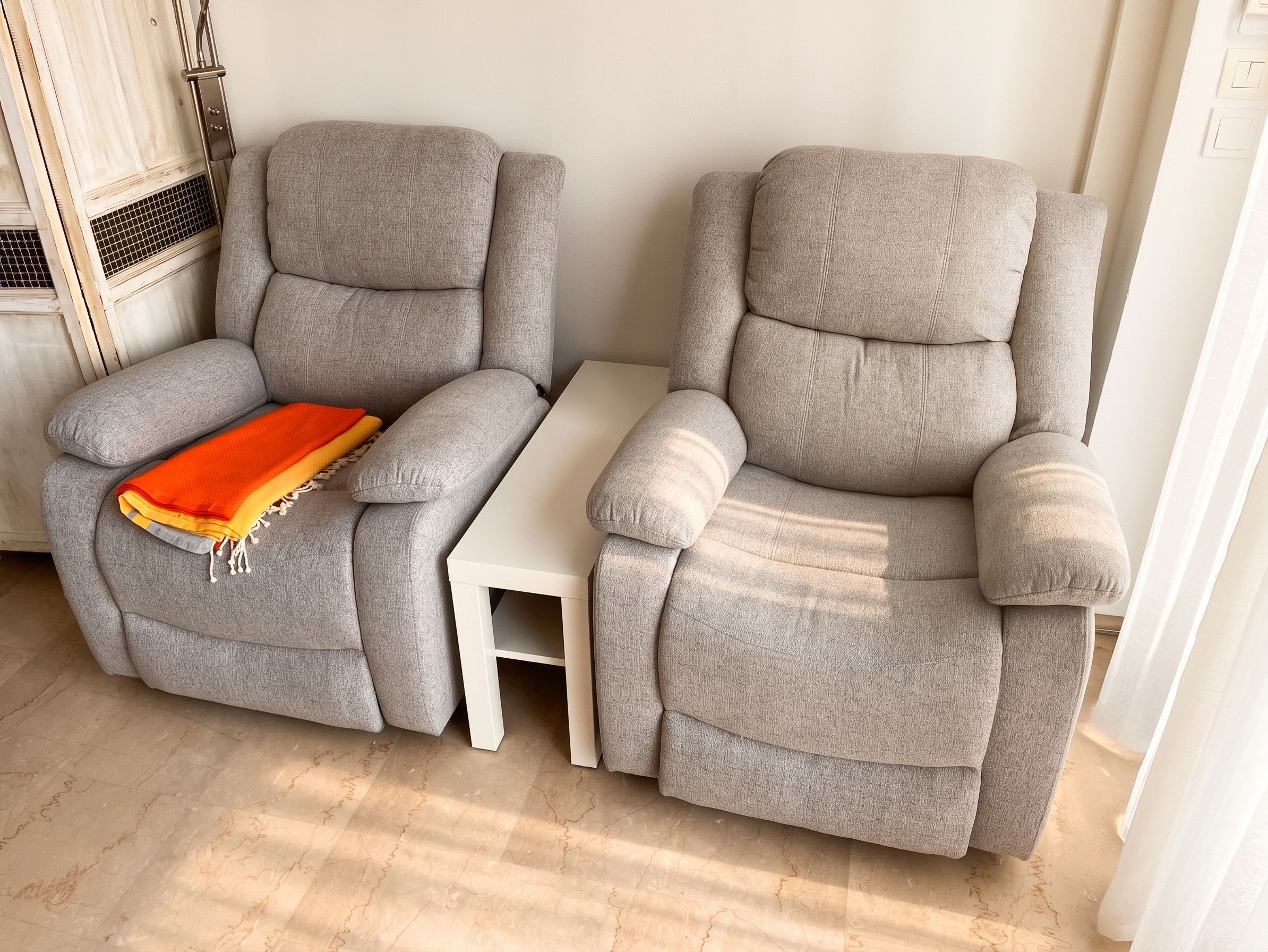 Two grey reclining chairs with a small white table between them.