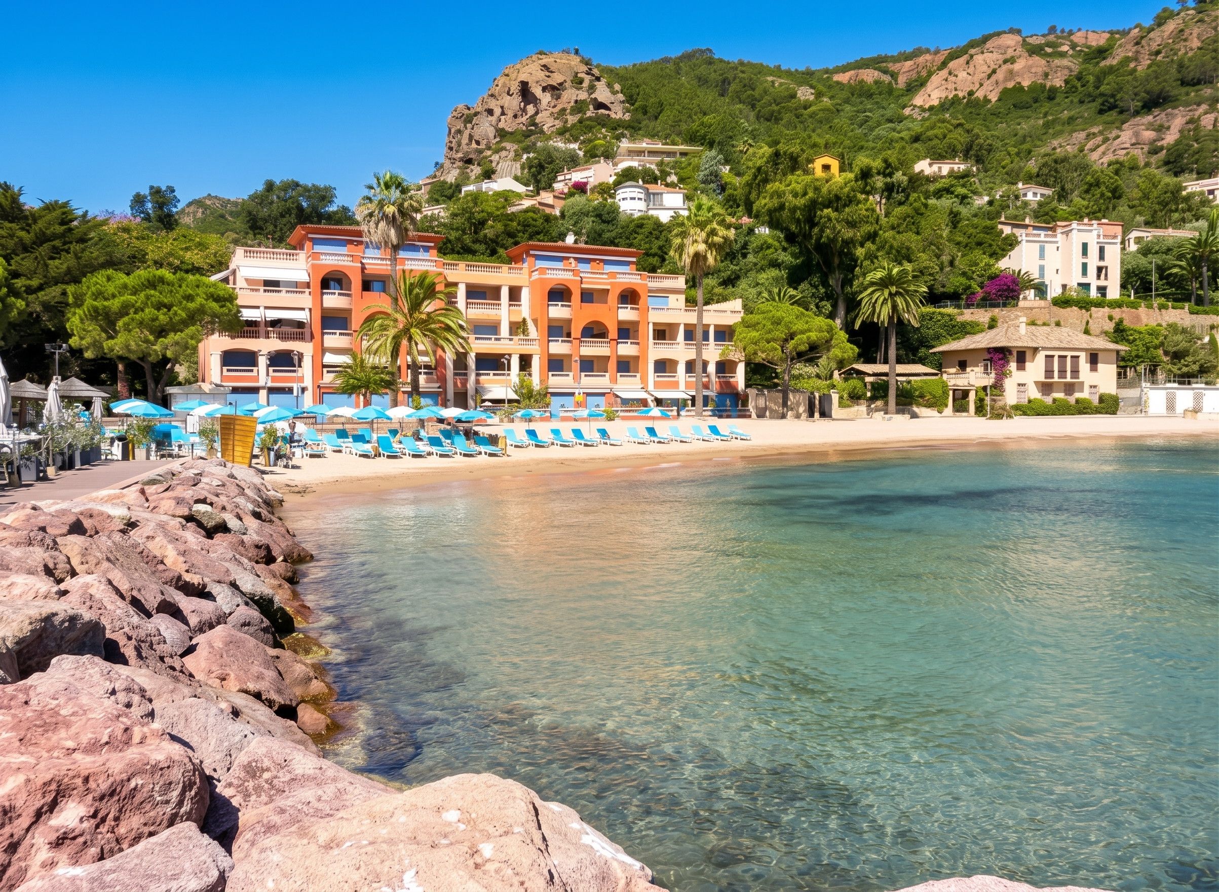 Un hotel frente al mar con playa, aguas cristalinas y un litoral rocoso.