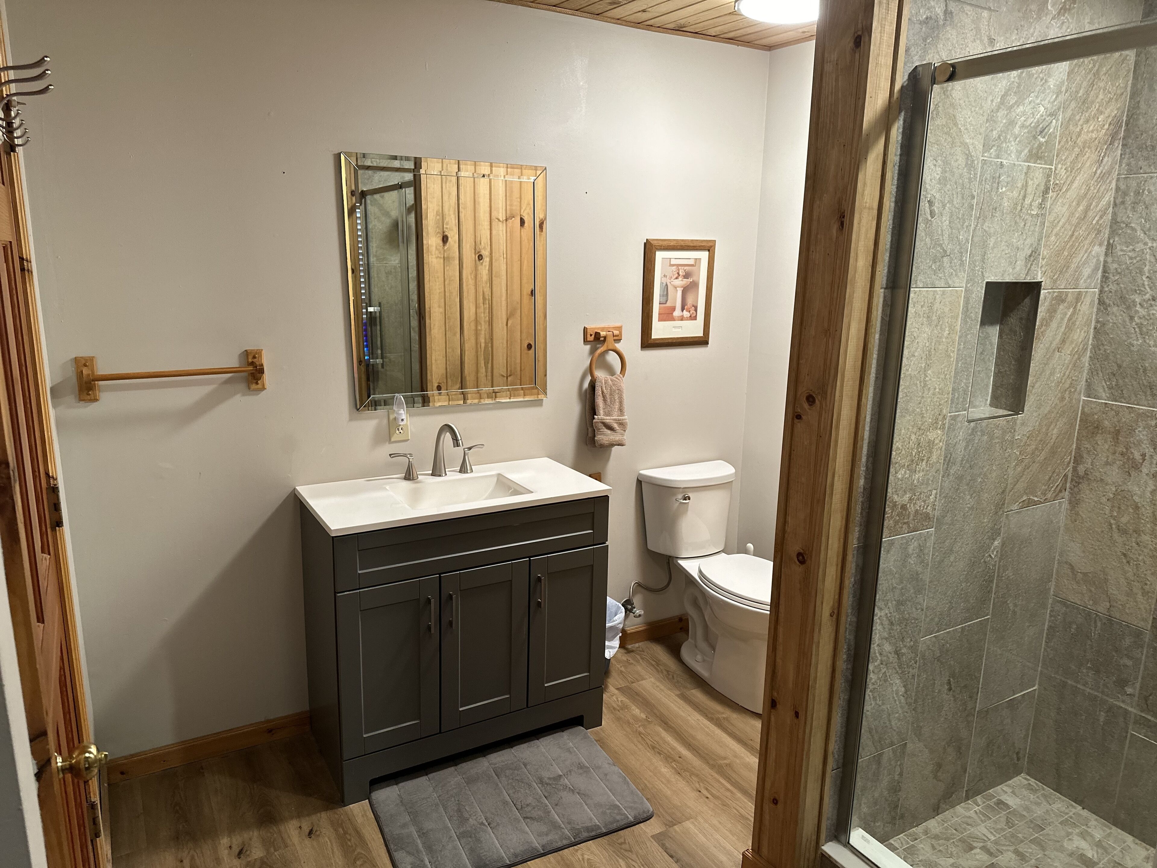Un bagno con un mobile lavabo in legno, un lavello, un WC e una zona doccia.