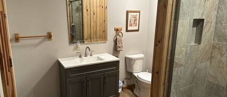 Un bagno con un mobile lavabo in legno, un lavello, un WC e una zona doccia.